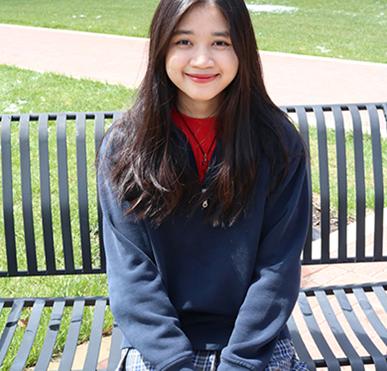 Happy student sitting outside wearing school uniform